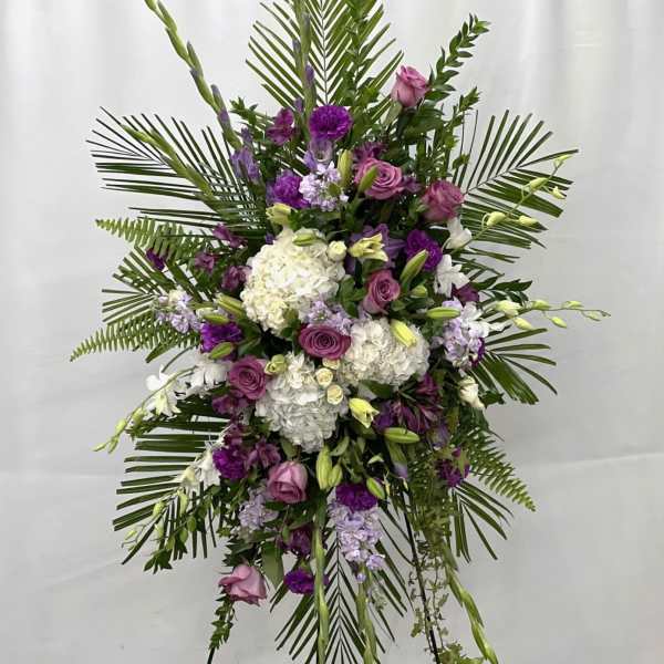 Standing floral spray with purple and white flowers on a tripod easel