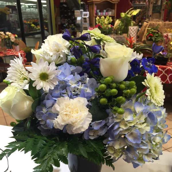 Blue and white mixed flower arrangement in a black vase