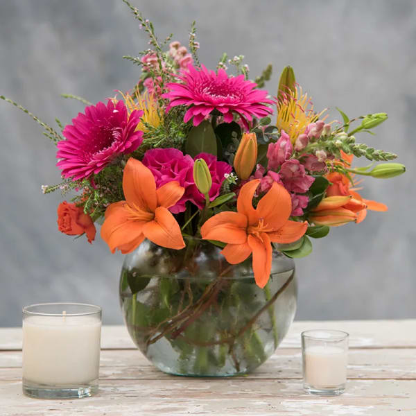 Bright mixed bouquet in a glass vase with candles nearby
