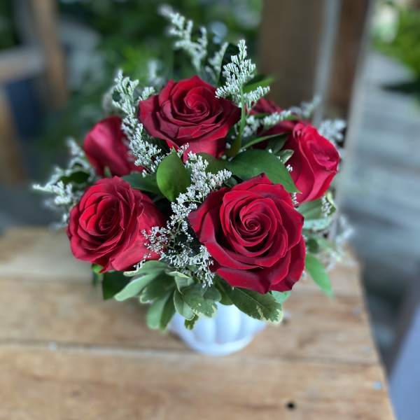 Bouquet of red roses with white filler in a small vase
