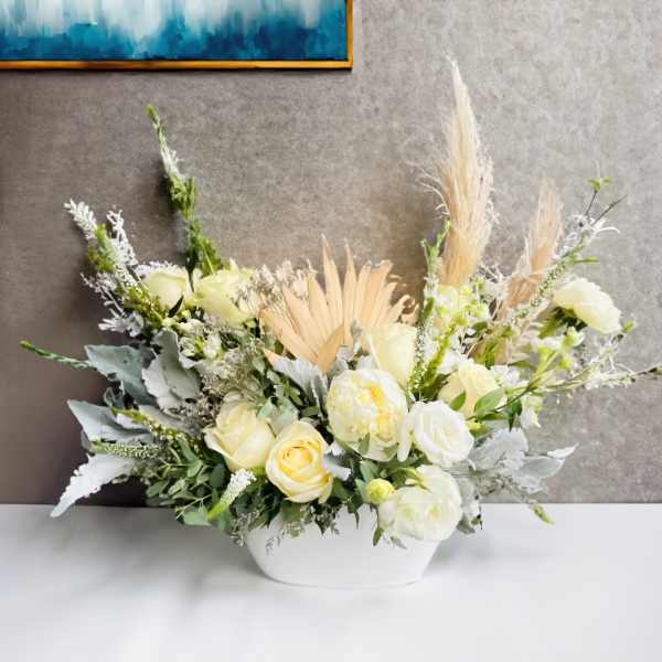 Cream and white floral arrangement in a white vase with dried grasses