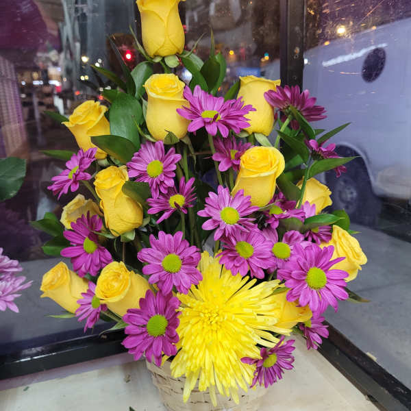 Basket arrangement of yellow roses and purple daisies