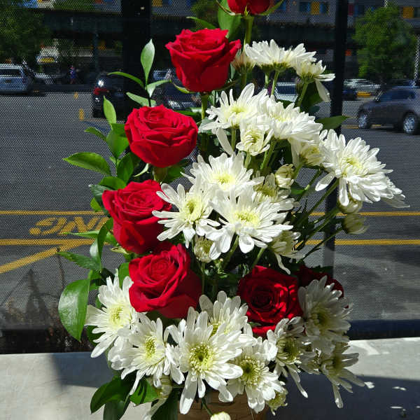 Basket arrangement of red roses and white daisies