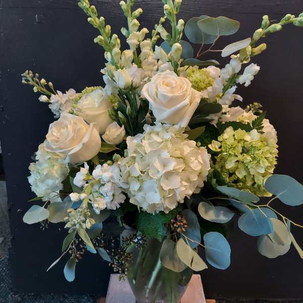 White roses and hydrangeas arranged in a glass vase with eucalyptus