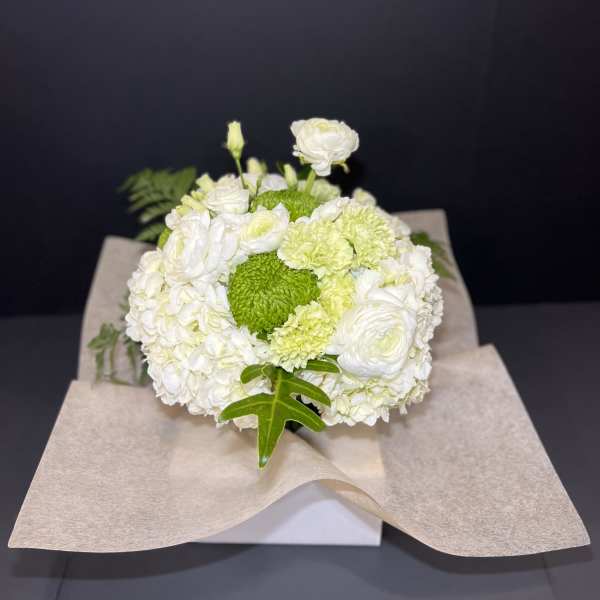 White and green floral bouquet wrapped in beige paper