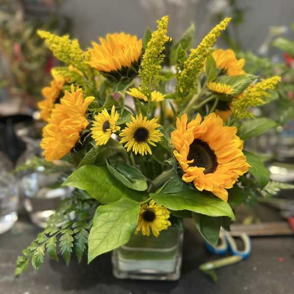 Sunflower and yellow daisy bouquet in a clear glass vase