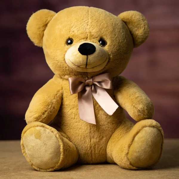 Plush teddy bear with a satin bow sitting against a blurred background