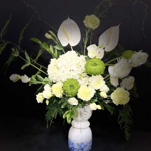 White floral arrangement in a blue-and-white vase with green accents