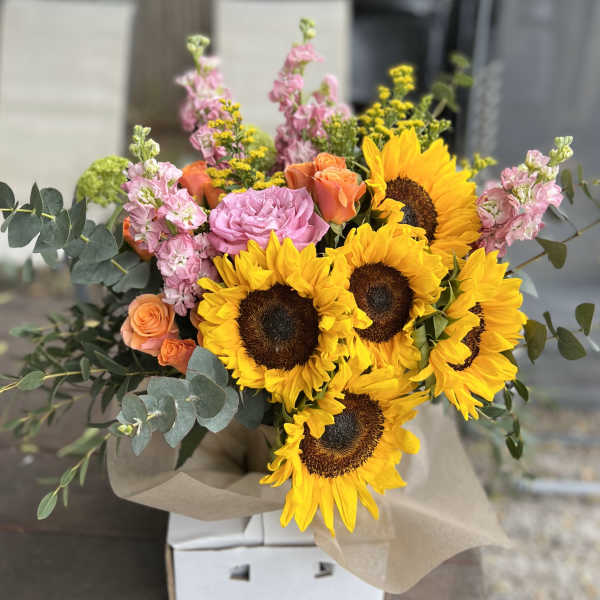 Bouquet of sunflowers, pink roses, and peach roses with eucalyptus