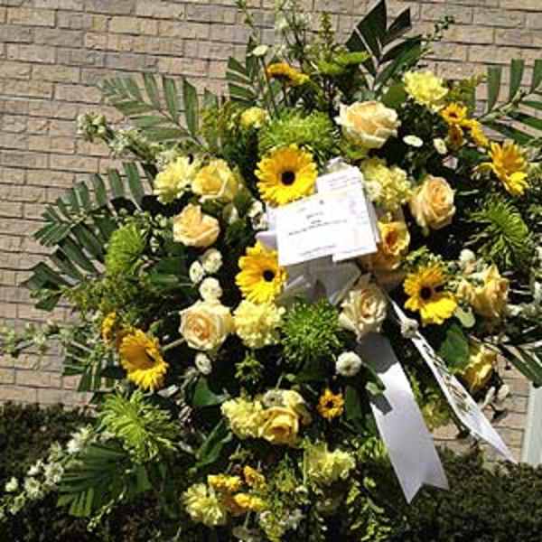 Large yellow and white funeral spray with ribbon on an easel