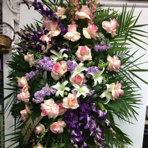 Large standing spray of pink roses, white lilies, and purple orchids