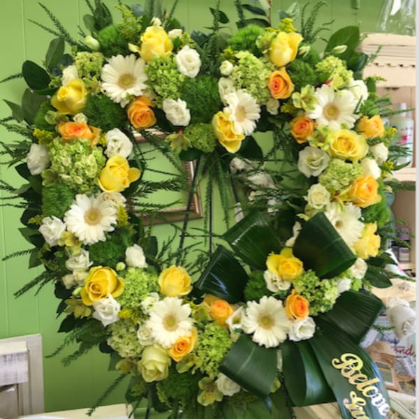 Large heart-shaped floral wreath with yellow and white flowers on an easel