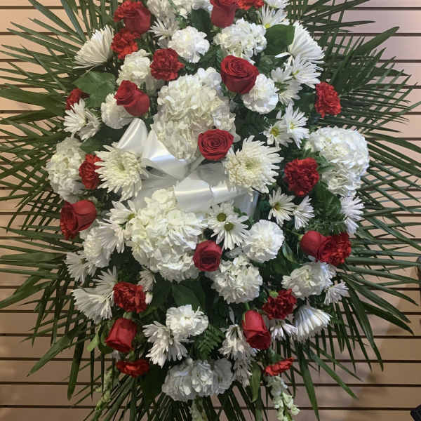 Standing floral spray with red roses and white flowers on a palm backdrop