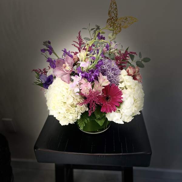 Mixed bouquet of white, pink, and purple flowers in a glass vase