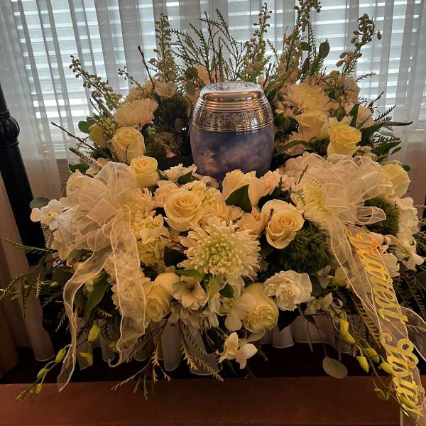 White floral funeral arrangement with a silver urn in the center