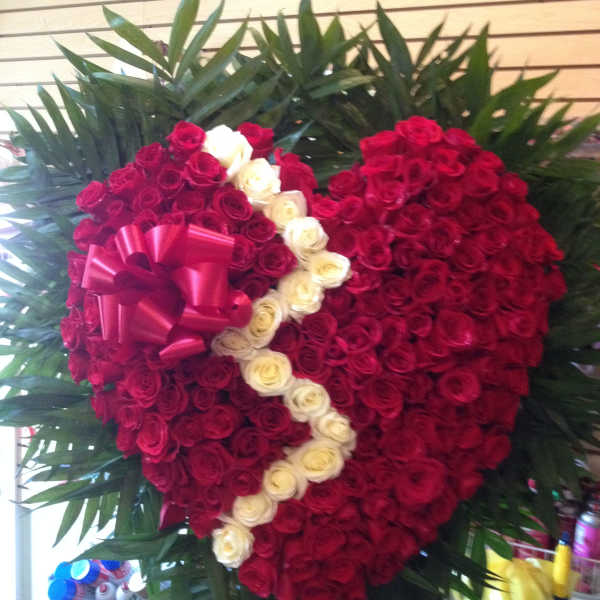 Heart-shaped rose arrangement with a pink ribbon and white rose accent