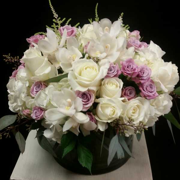 Bouquet of white roses, white orchids, and lavender spray roses in a round vase