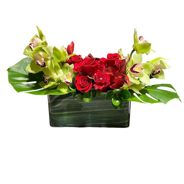Red roses and green orchids in a rectangular glass vase
