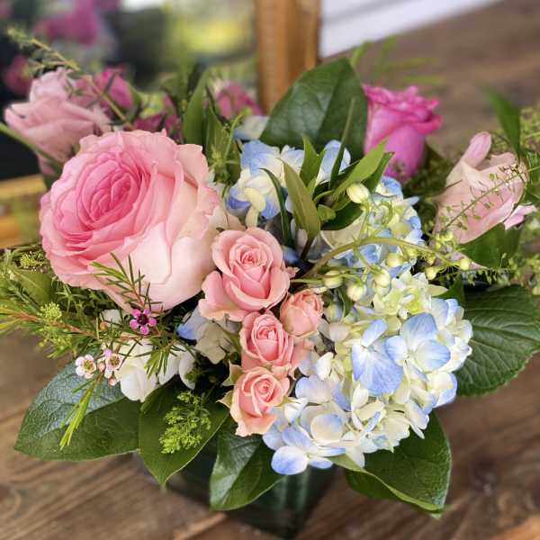 Pink roses and blue-white hydrangeas in a glass vase