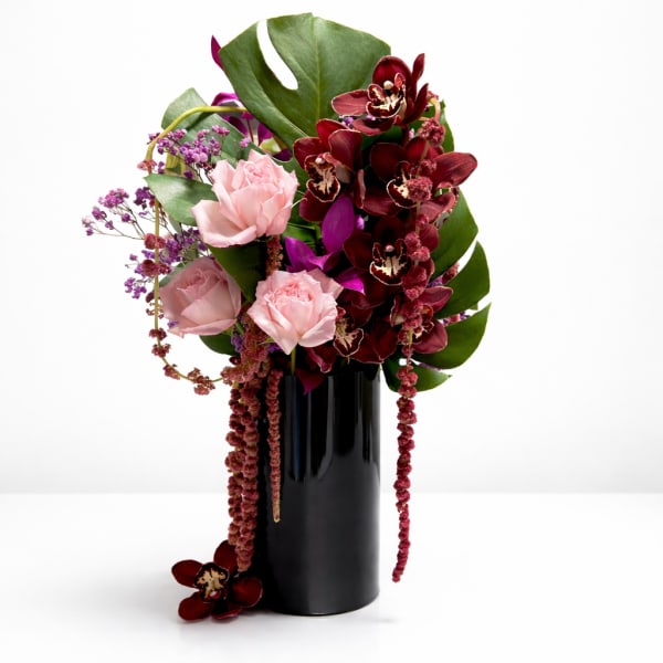 Pink roses and burgundy orchids in a black vase