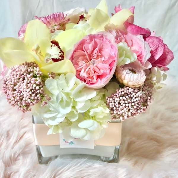 Pink and cream floral arrangement in a square glass vase