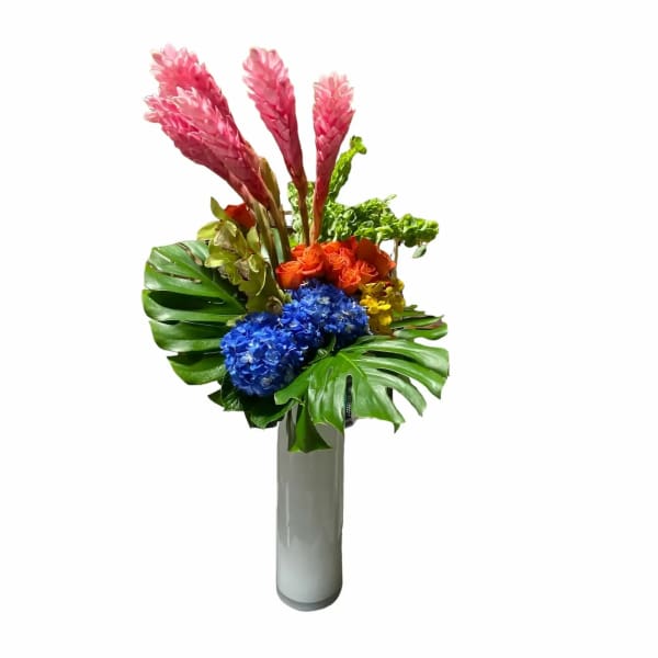 Tropical bouquet with pink plumes, blue hydrangeas, and orange roses in a tall vase