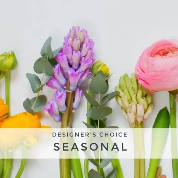 Stems of yellow, purple, and pink seasonal flowers laid in a row on a white background