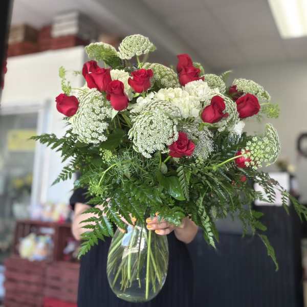 Bouquet of red roses and white flowers in a clear glass vase