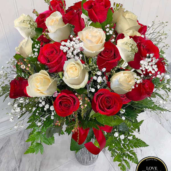 Tall vase arrangement of red and cream roses with baby's breath and a red ribbon
