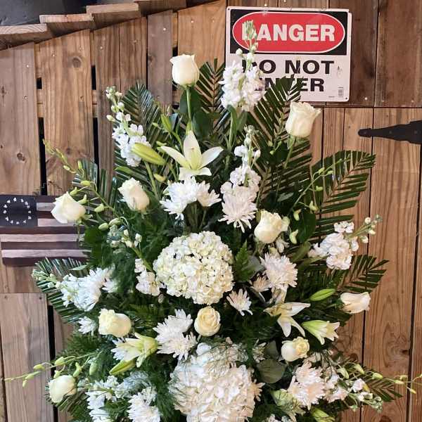 White funeral spray with roses, lilies, and hydrangeas on a stand