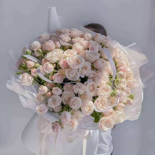 Large bouquet of pale pink roses wrapped in white paper