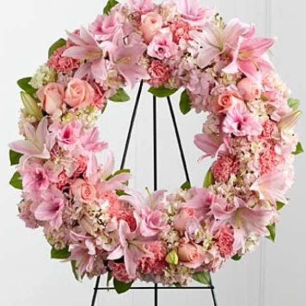 Pink floral wreath on a black stand