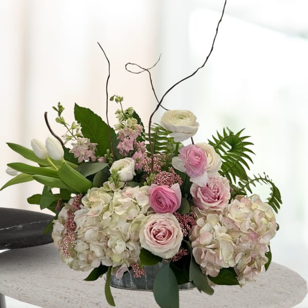 Pink and white floral arrangement in a low metal container