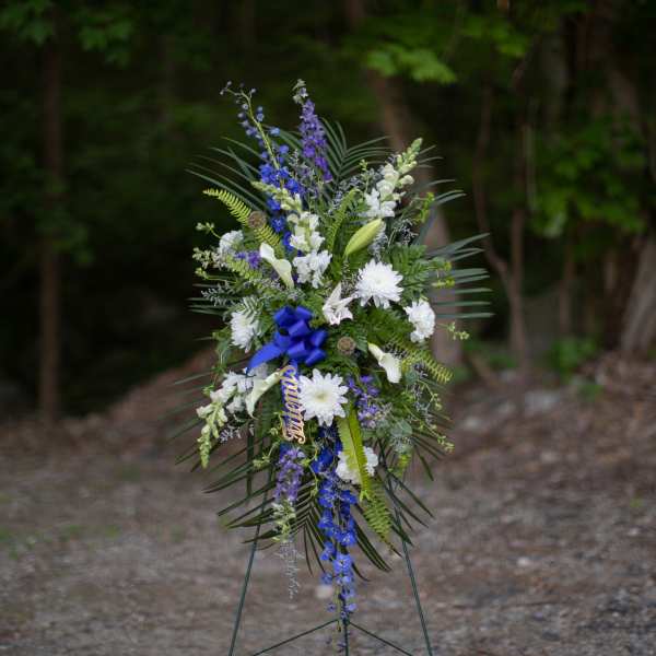 Tall standing floral spray with white and blue flowers on an easel