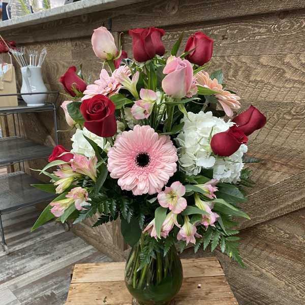 Bouquet of red and pink roses with a pink gerbera daisy in a glass vase