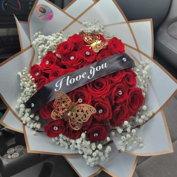 Red rose bouquet with baby’s breath and a black ribbon reading "I love you"