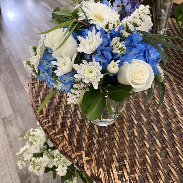 Blue and white flower arrangement in a clear glass vase