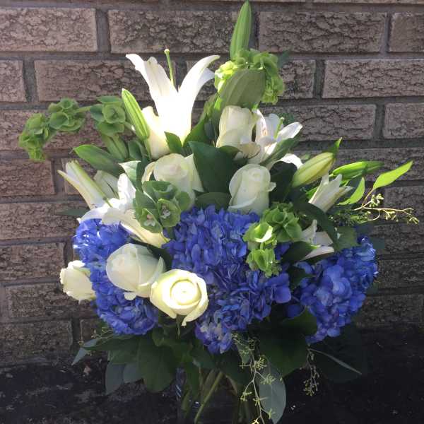 Blue hydrangeas and white lilies in a glass vase