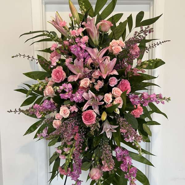Large pink floral standing spray with roses and lilies on an easel