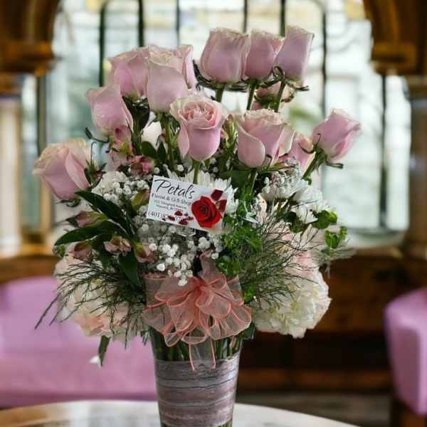 Pink roses arranged in a clear glass vase with a pink ribbon bow