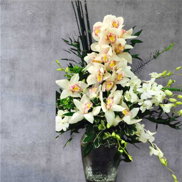 White orchid arrangement in a dark glass vase