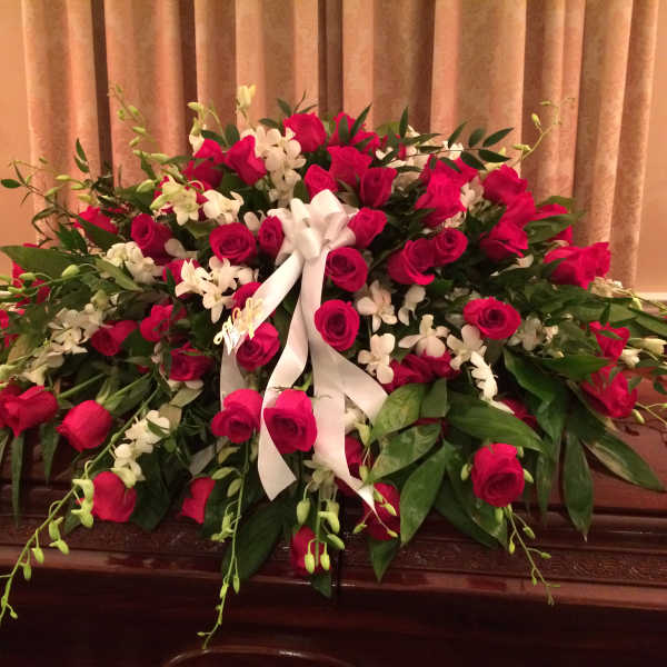Large casket spray of red roses and white orchids with a white ribbon