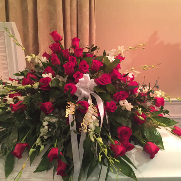 Large red rose casket spray with white ribbon and orchids