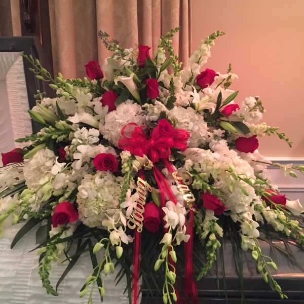 Large floral spray of white blooms and red roses with a ribbon bow