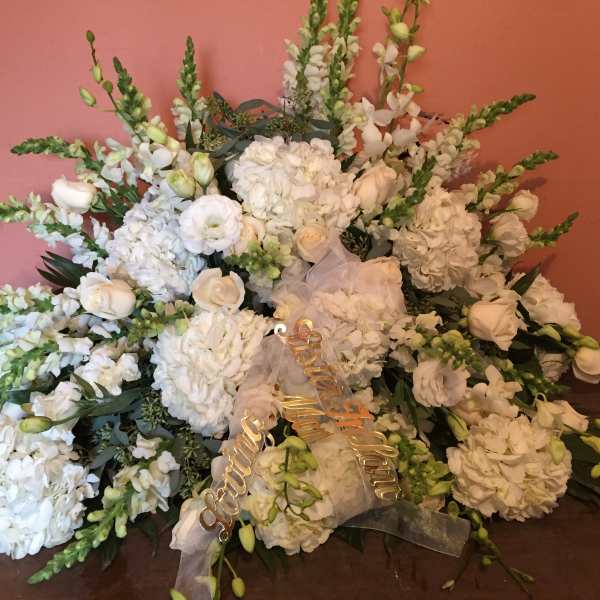 Large white floral arrangement with roses and hydrangeas on a table