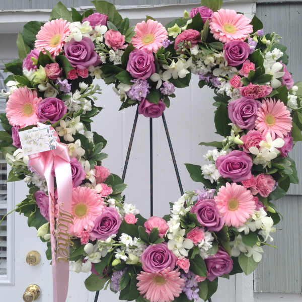 Heart-shaped floral wreath with pink gerberas and purple roses on an easel