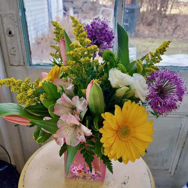 Mixed bouquet in a pink vase with yellow, purple, pink, and white flowers
