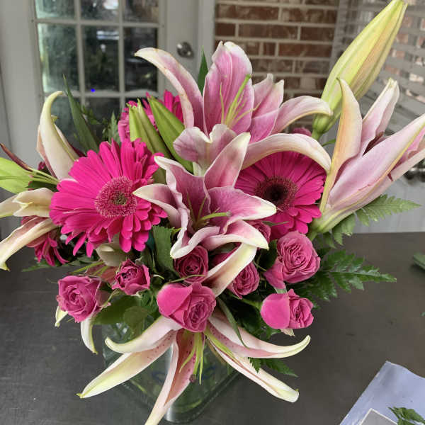 Pink lilies, gerbera daisies, and roses in a glass vase