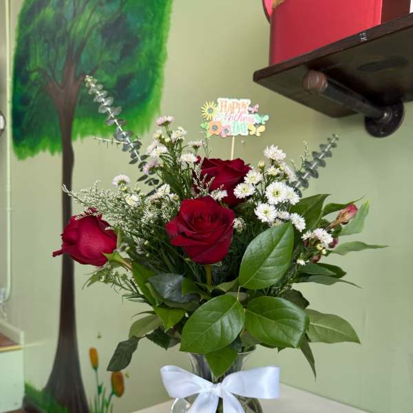 Red roses in a glass vase with a white ribbon and Mother's Day card