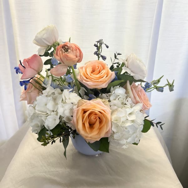 Peach and white roses with white hydrangeas in a pale vase